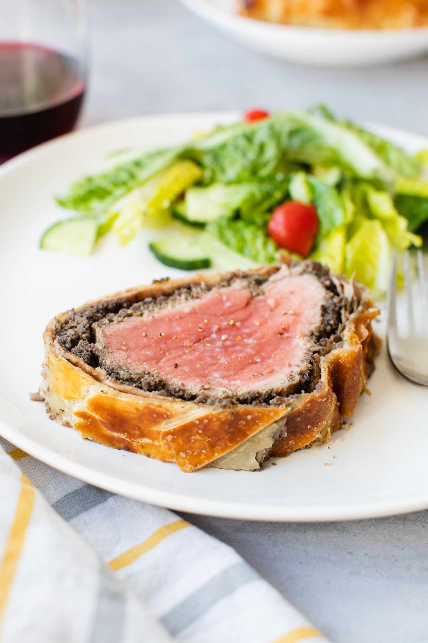 Slice of Beef Wellington on a Plate with a Side Salad