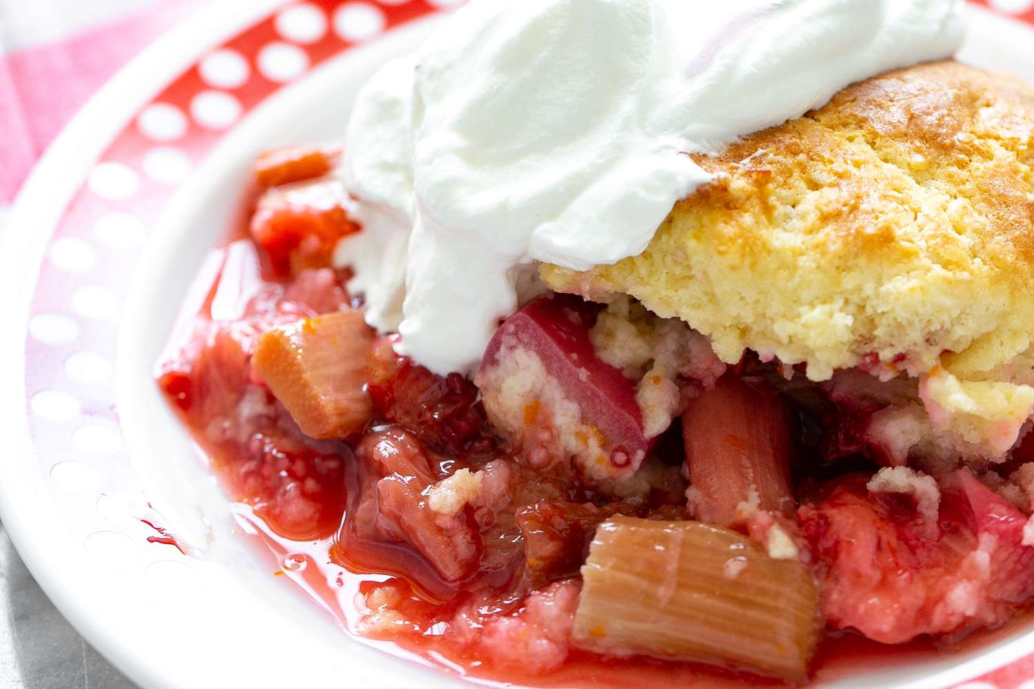 Bowl of Strawberry Rhubarb Cobbler Topped With Whipped Cream