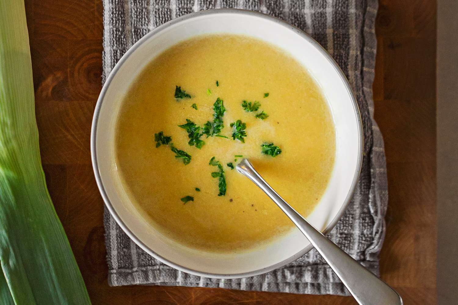 Bowl of soup garnished with fresh herbs on a wooden table