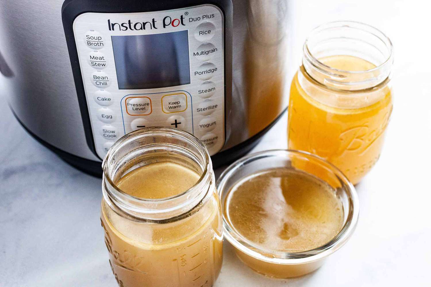 Instant Pot Chicken Stock - jars filled with chicken stock in front of an Instant Pot 