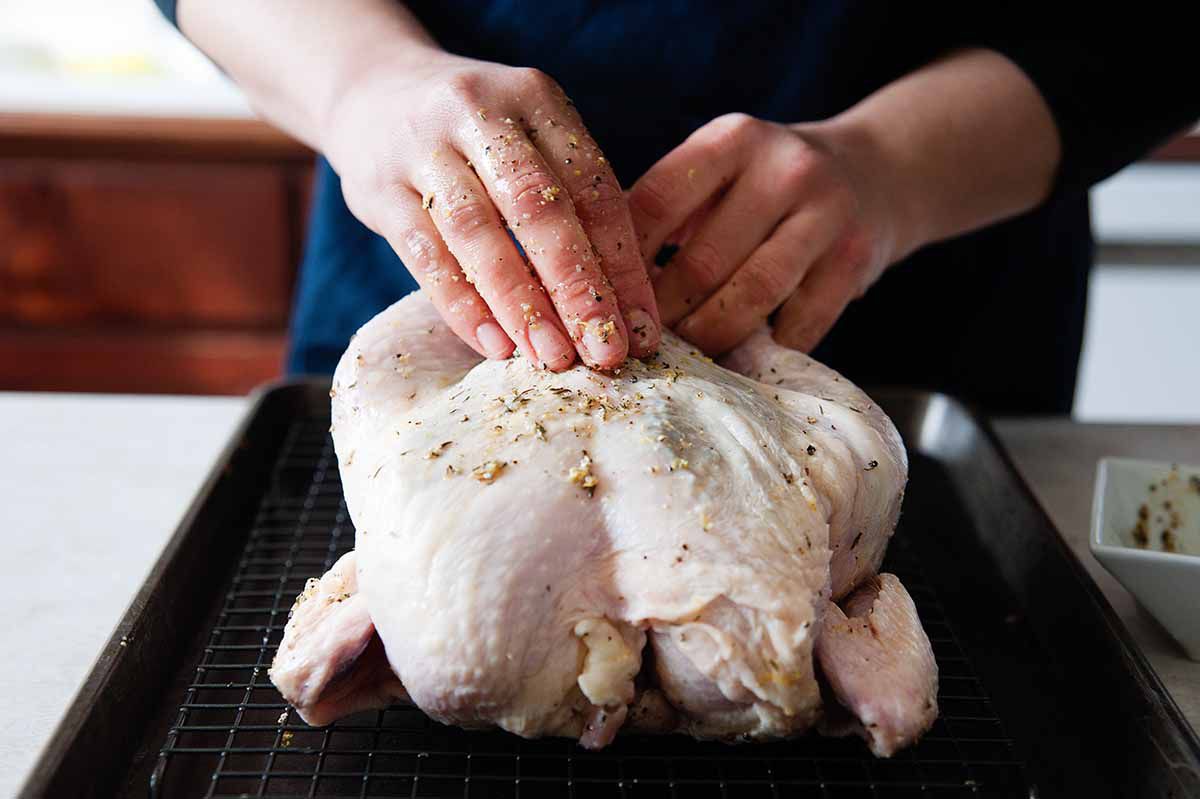 Oven Roasted Chicken Recipe - whole chicken being rubbed in herbs and oil