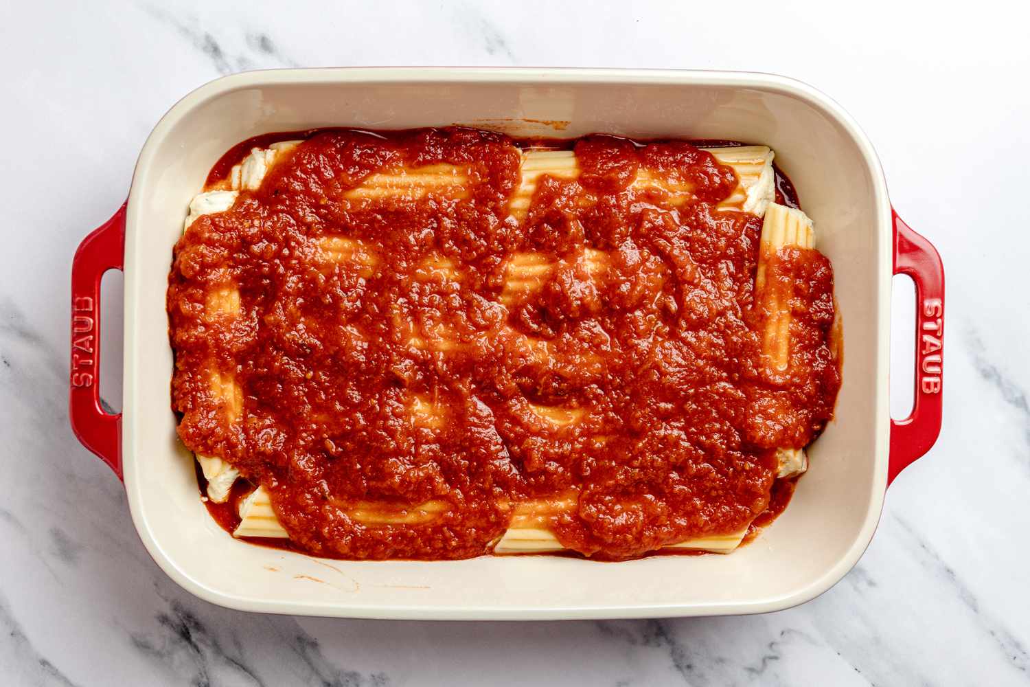 Manicotti in Casserole Dish Covered With a Layer of Marinara Sauce