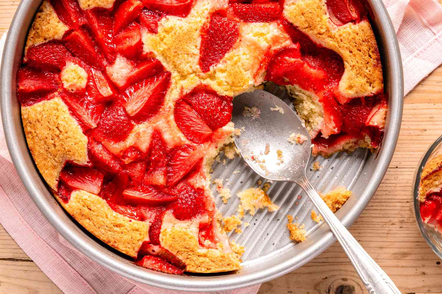 pan of strawberry spoon cake (missing a few bites) with a spoon resting in the pan
