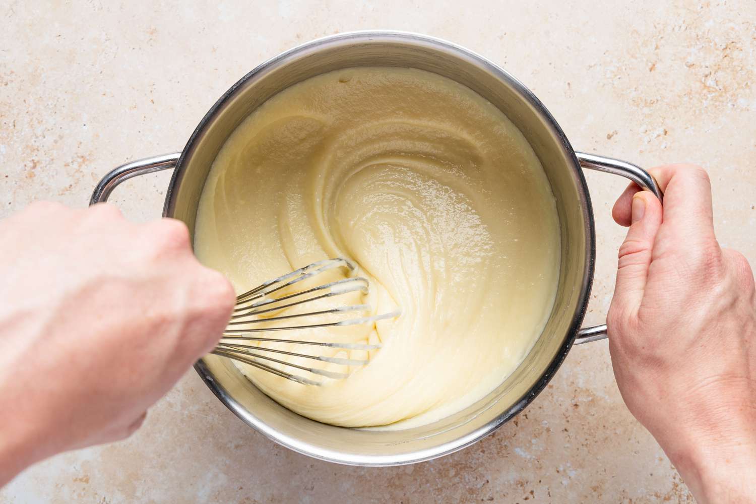 hand whisking thickened mixture in a pot for Migliaccio (Italian Ricotta and Semolina Cake)