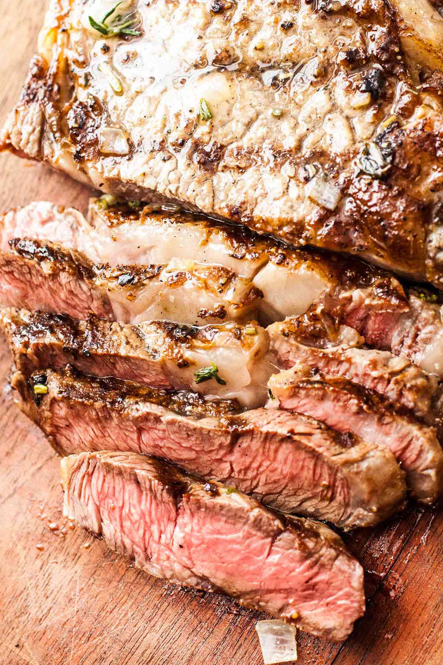 Sliced grilled ribeye steak on a wooden cutting board