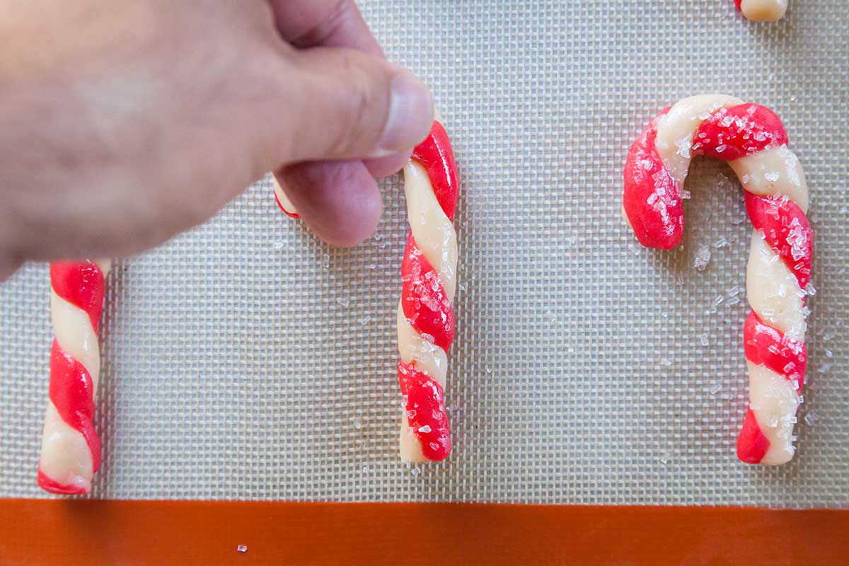 Hand Sprinkling Sugar on Candy Cane Cookies
