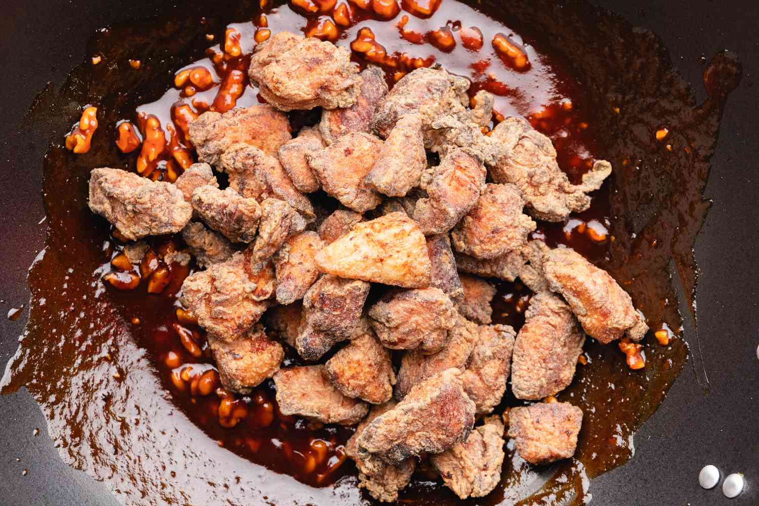 Korean fried chicken in wok with sweet and spicy sauce.