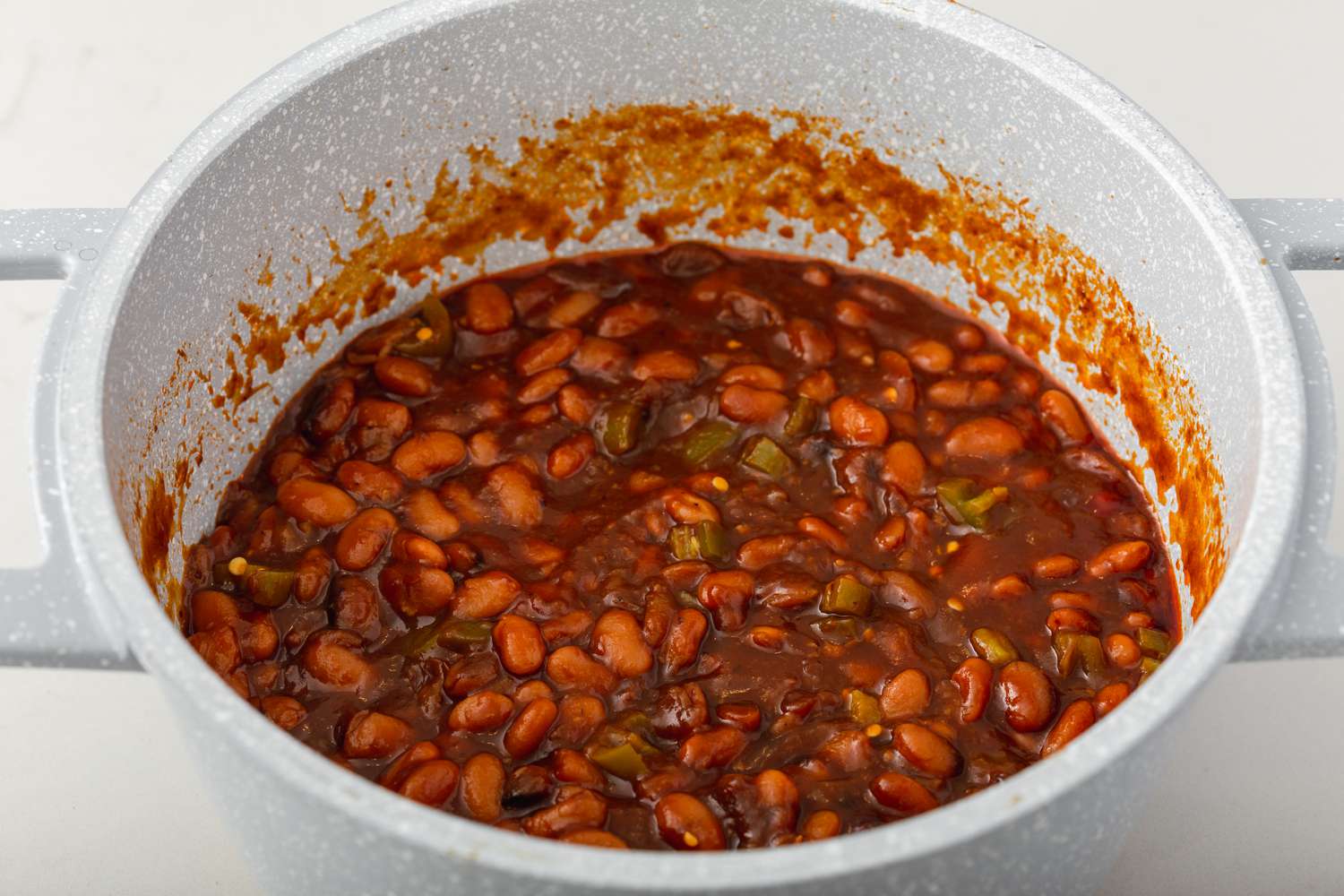 A dutch oven with pinto beans and ham inside.