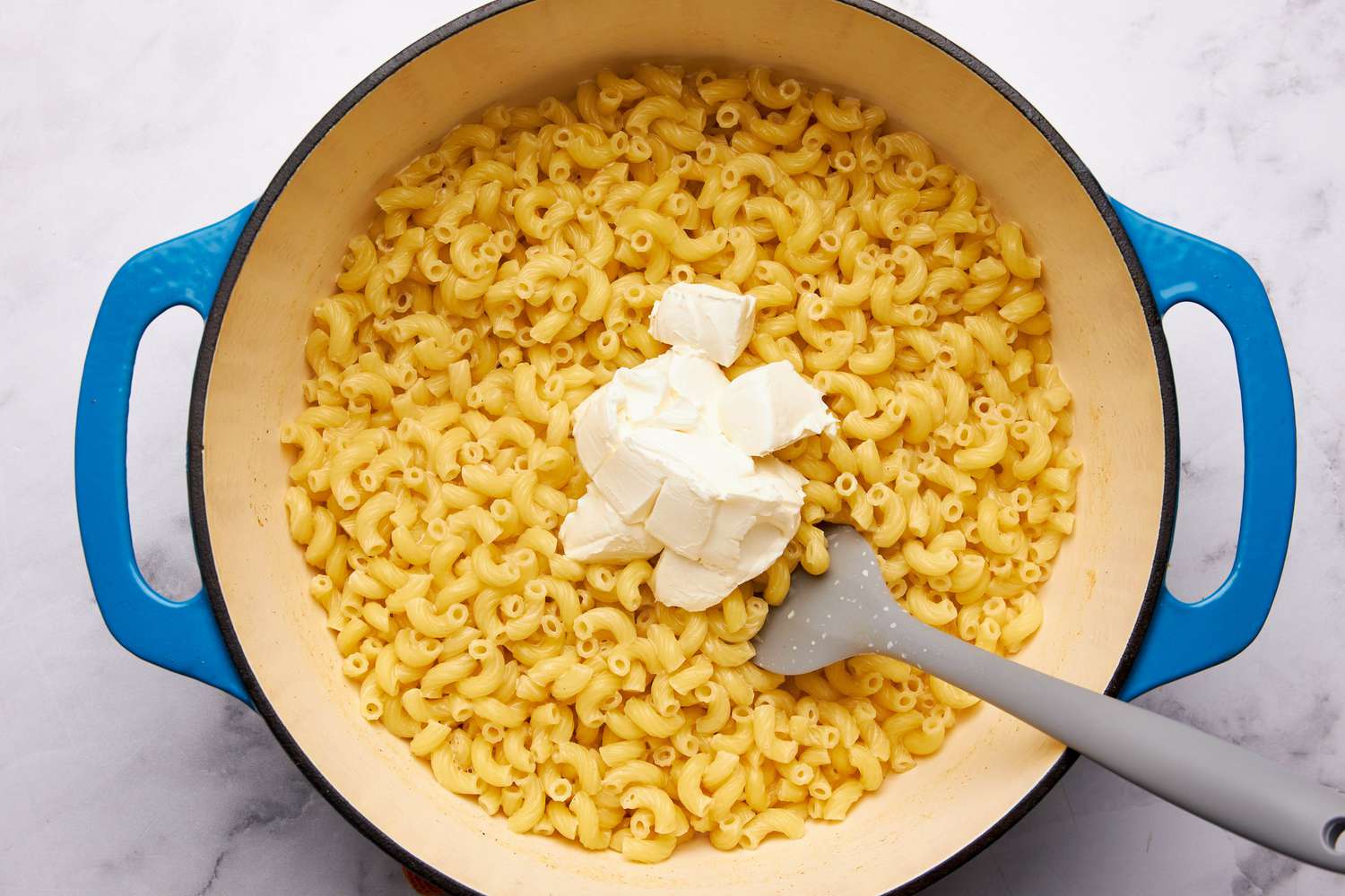 Cubes of cream cheese added to dutch oven for mac'n'cheese one pot recipe