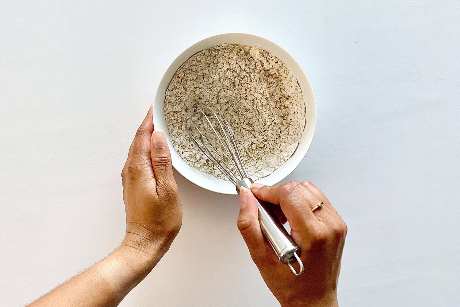 Whisking dry ingredients in a bowl to make Gluten-Free Sheet Pan Monster Cookies.