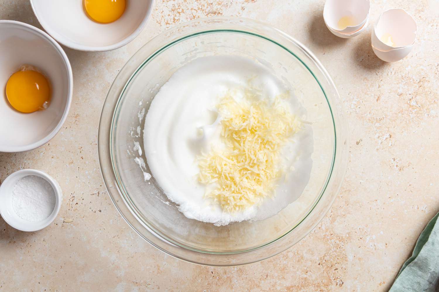 Adding cheese to a bowl of whipped egg whites for a Cloud Eggs recipe