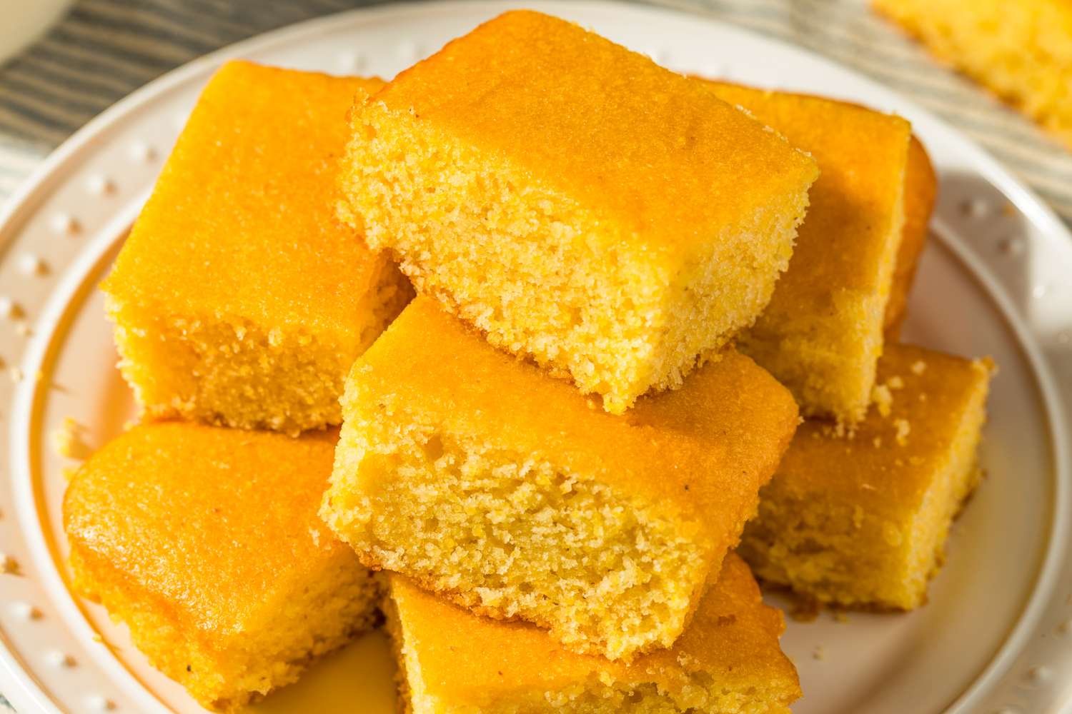 A stack of square cornbread pieces on a white plate