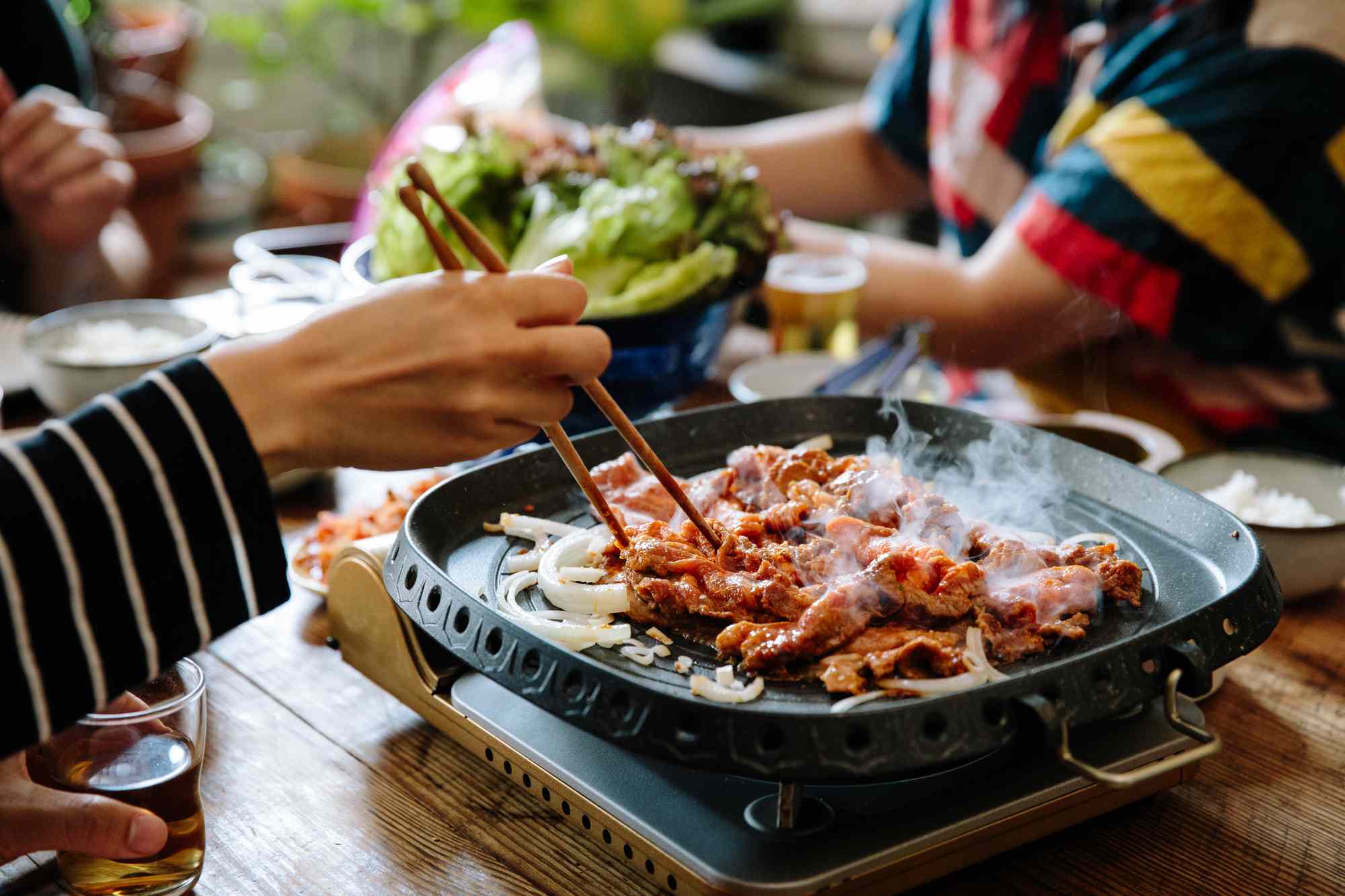 Cooking Korean BBQ with chopsticks on an electric cooktop 