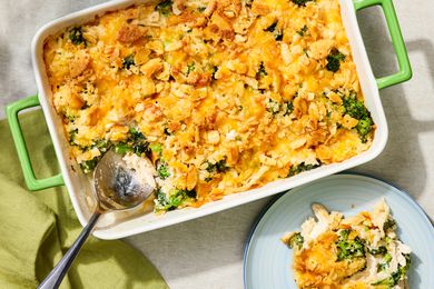 Overhead view of chicken and broccoli casserole in a green dish with a serving spoon next to a small plate with a serving