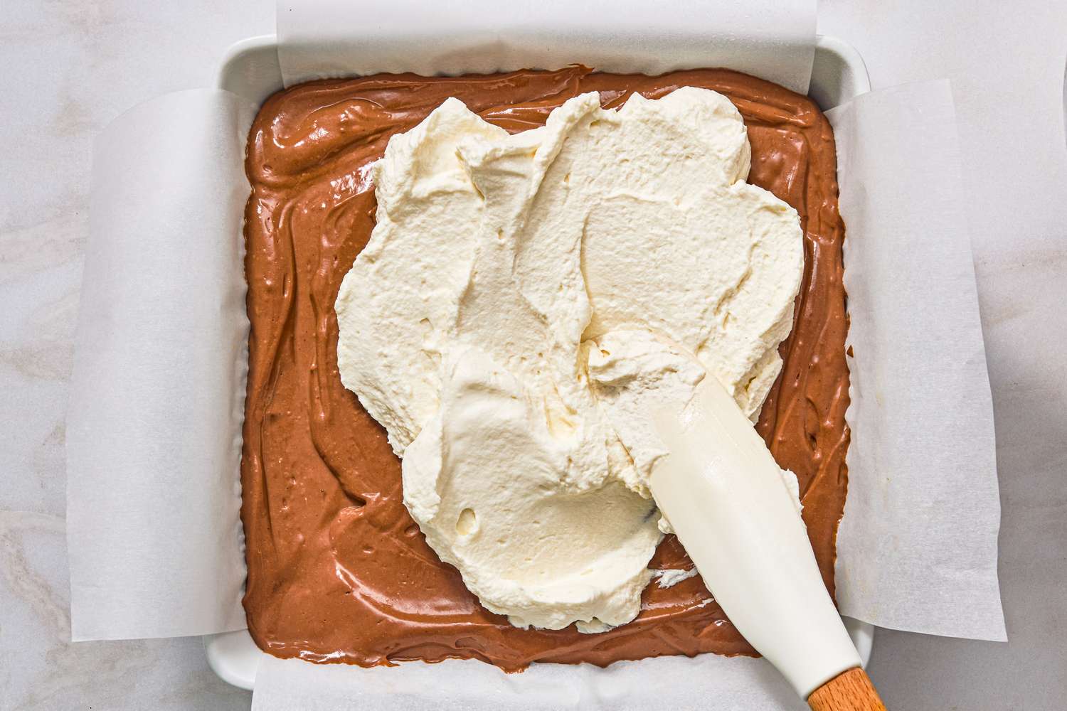 overhead view of whipped cream topping being added to Chocolate-Peanut Butter Delight