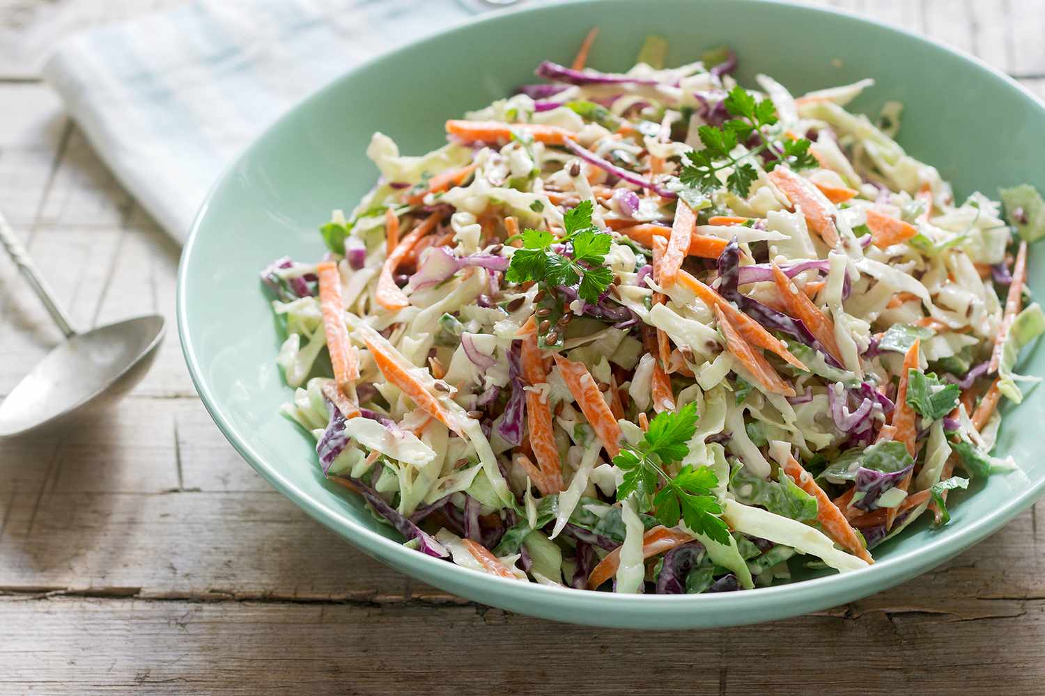 Bowl of coleslaw with shredded vegetables on a wooden table