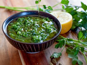 Zhoug in a small black bowl with olive oil on top.