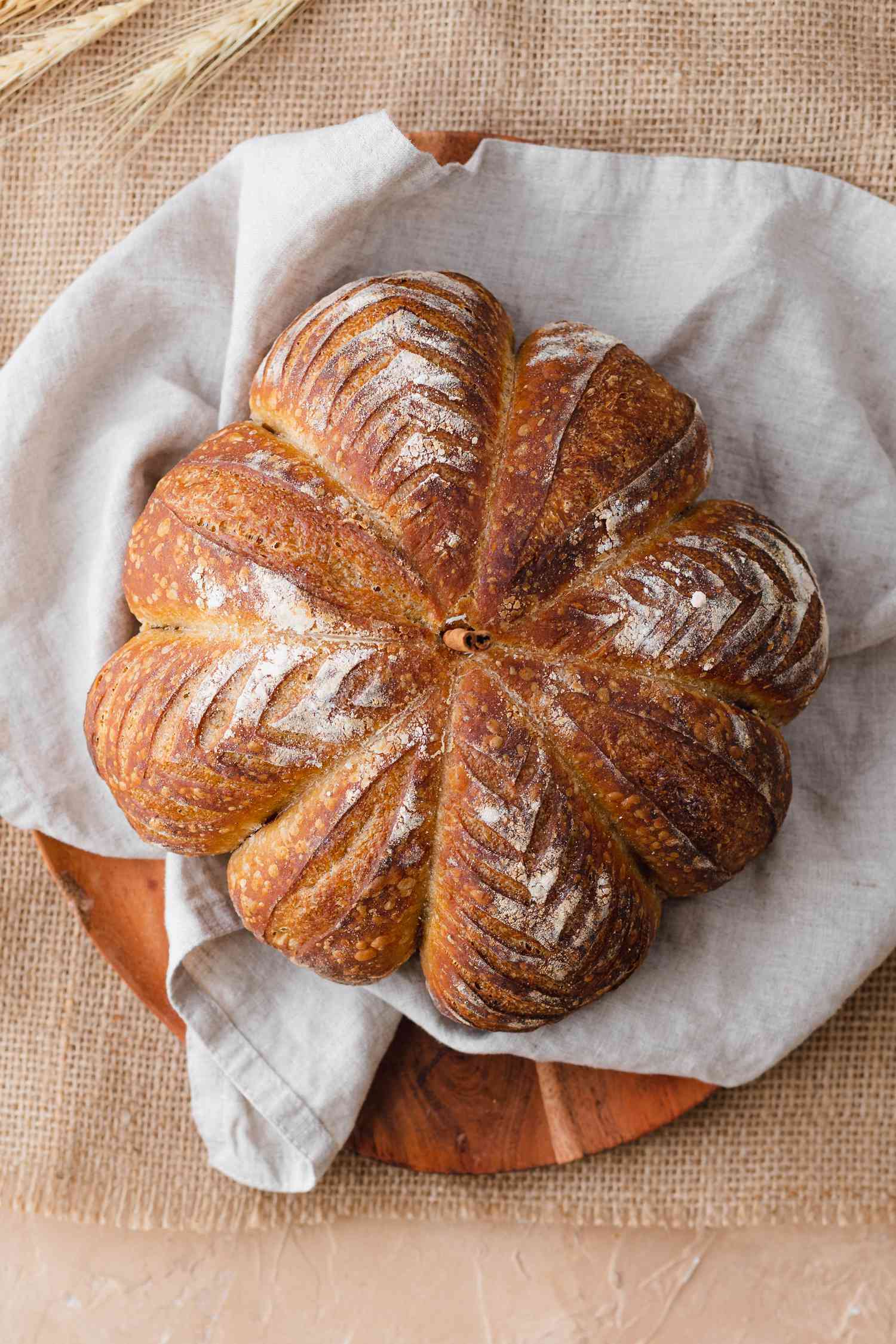 Overhead view of spiced pumpkin-shaped sourdough on a grey linen.