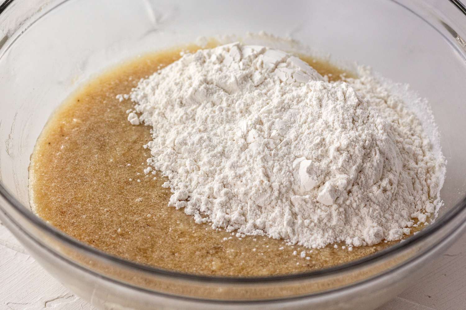 Flour added to a bowl of wet ingredients to make banana bread.