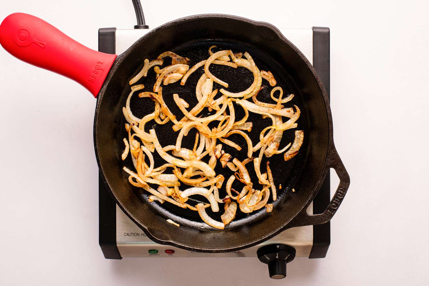 sauteed sliced onions in a cast iron skillet for Lyonnaise potatoes recipe
