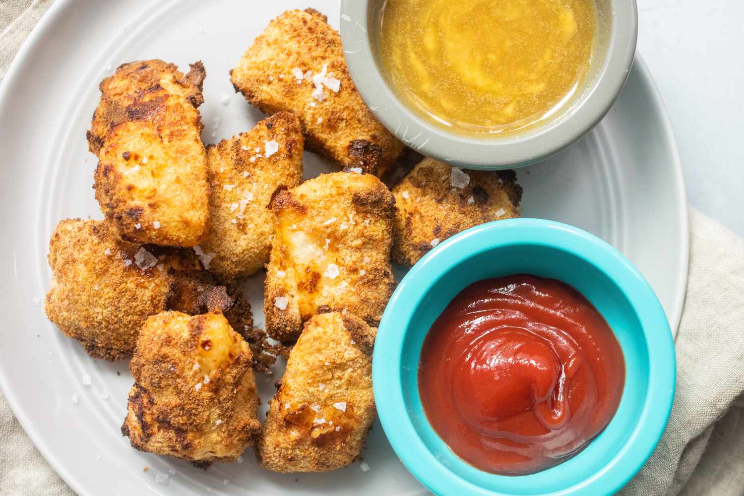 Best Air Fryer Chicken Nuggets on a plate with ketchup and mustard.