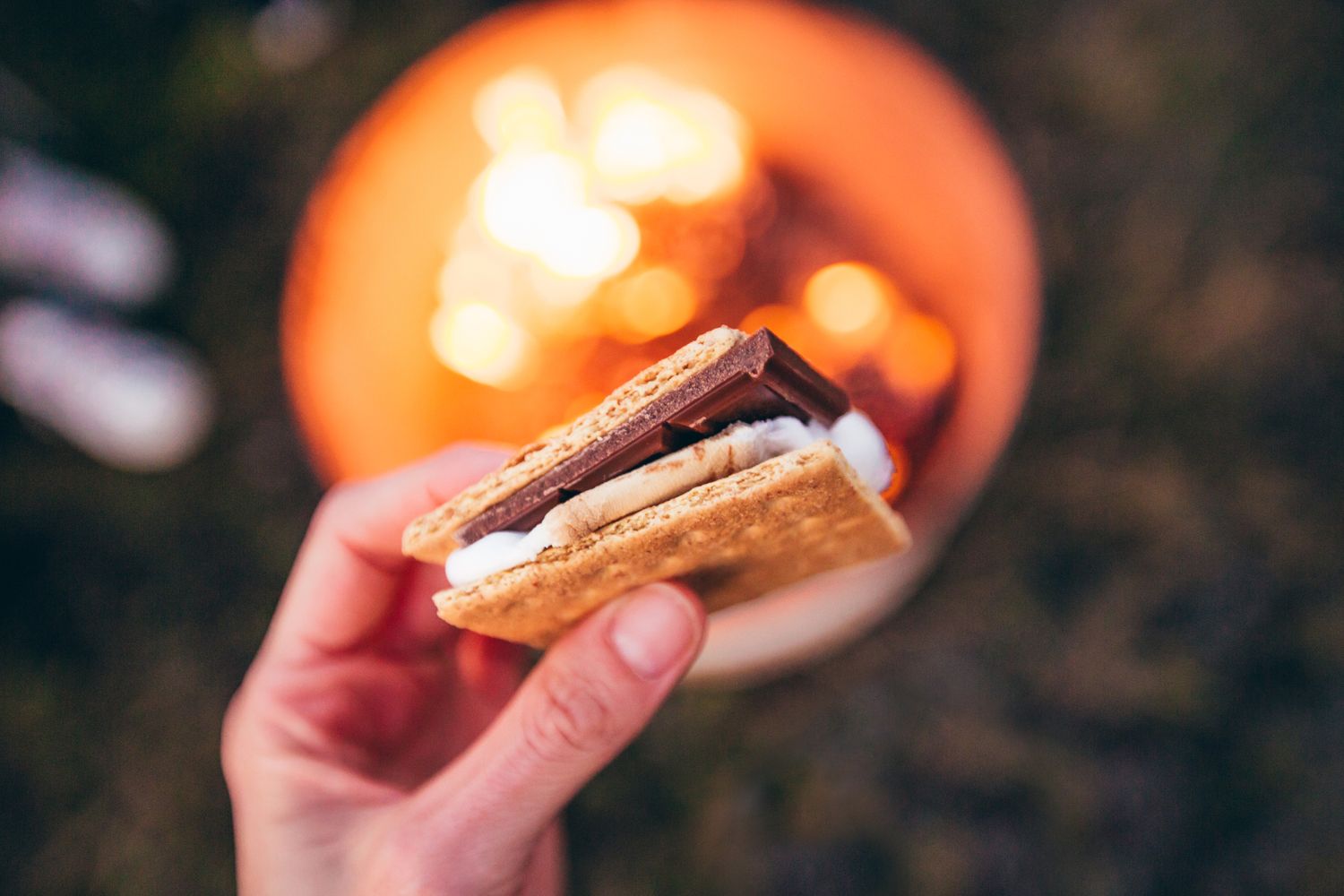 Person Holds a S'more From a S'mores Bar at a Wedding 