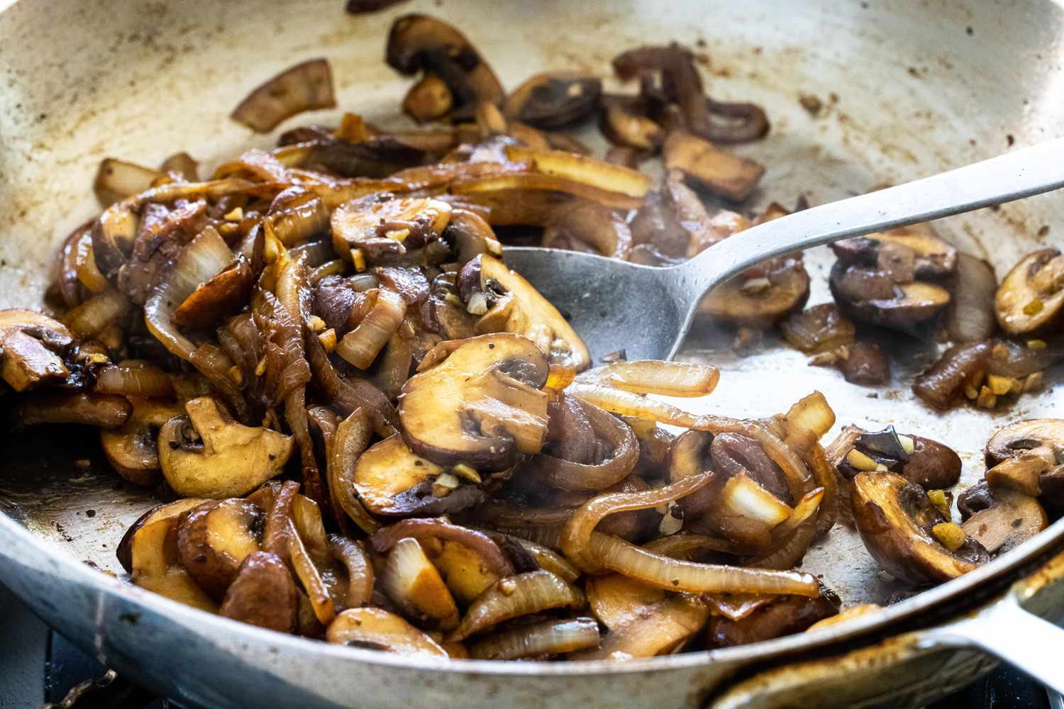 Caramelized onions and mushrooms in a skillet to make goat cheese crostini with mushrooms.