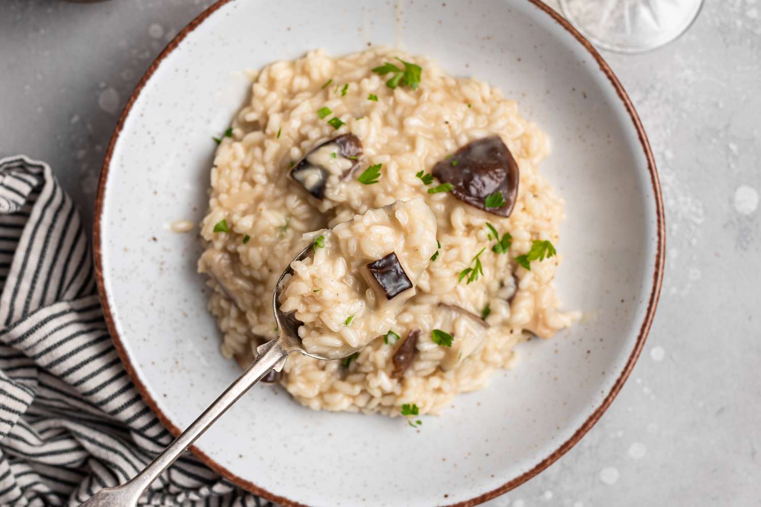 A bowl of mushroom risotto with a spoon scooping risotto out of the bowl.