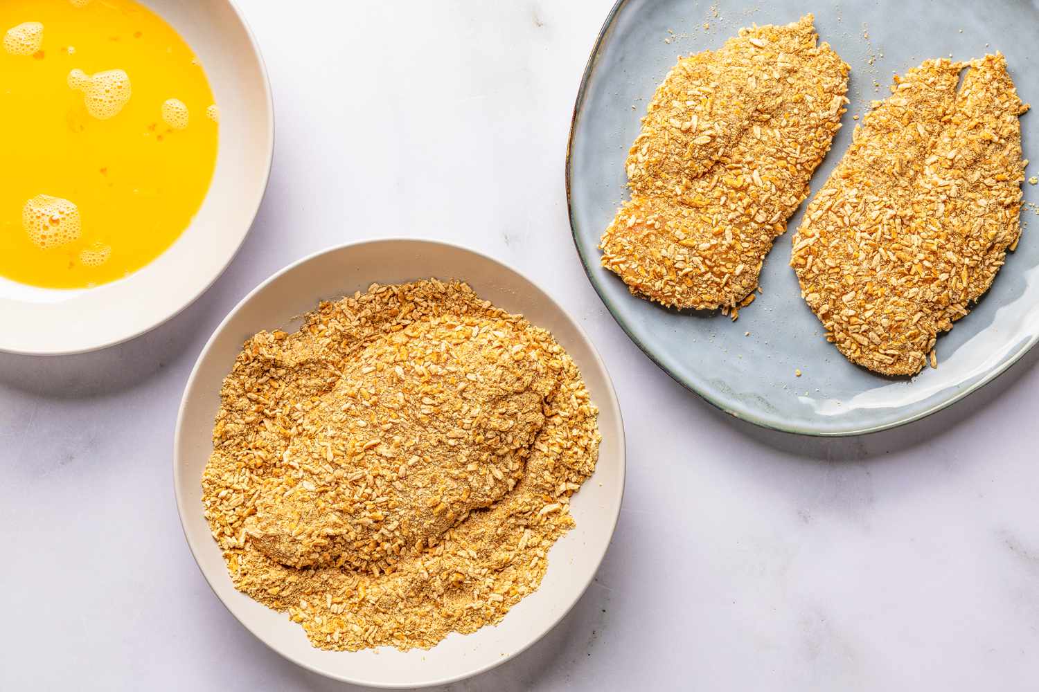 chicken cutlets dredged and placed on a plate for pretzel chicken recipe
