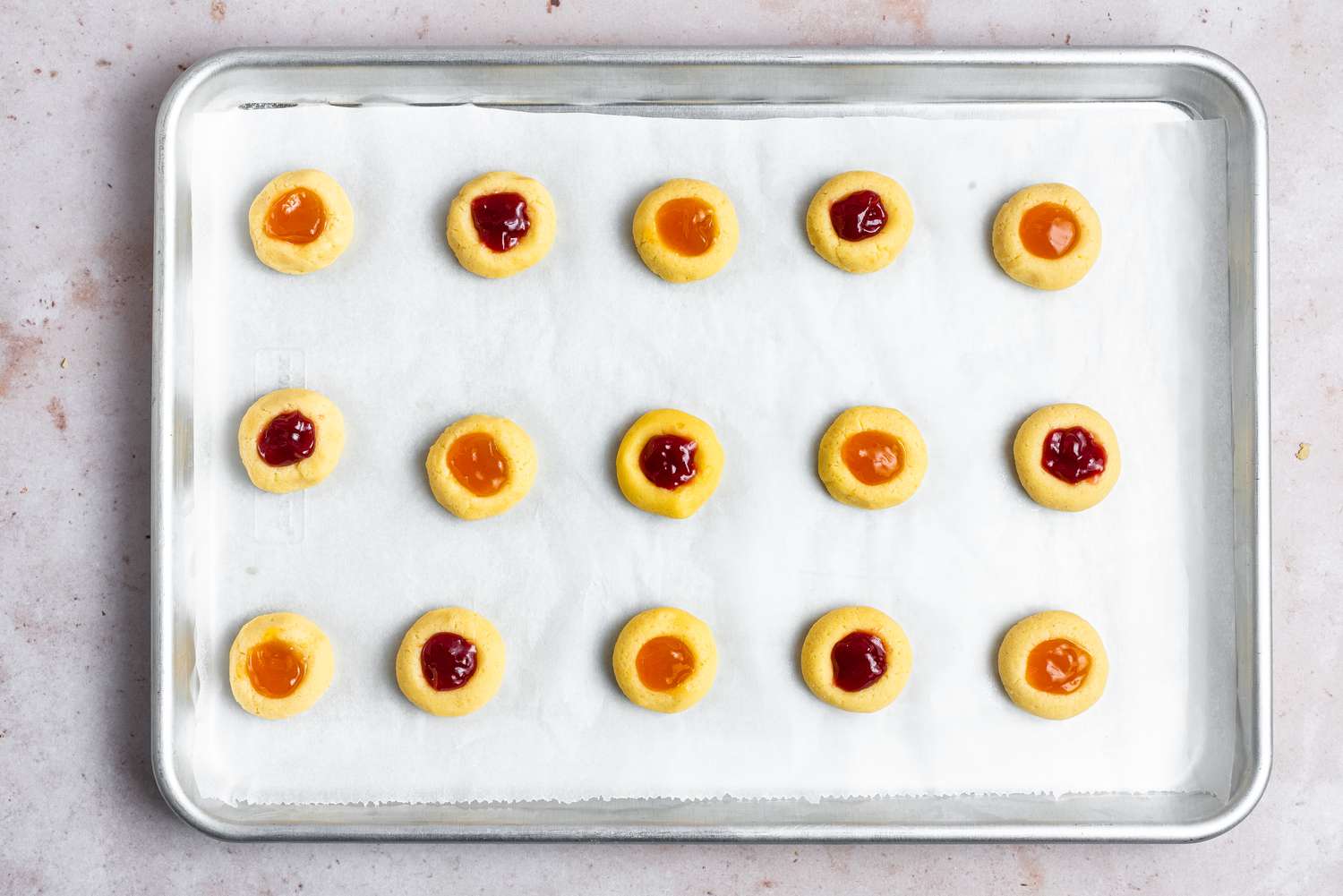 Thumbprint cookies on a baking sheet and filled with a variety of jams.
