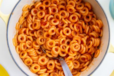 Bowl of ringshaped pasta in tomato sauce with a spoon
