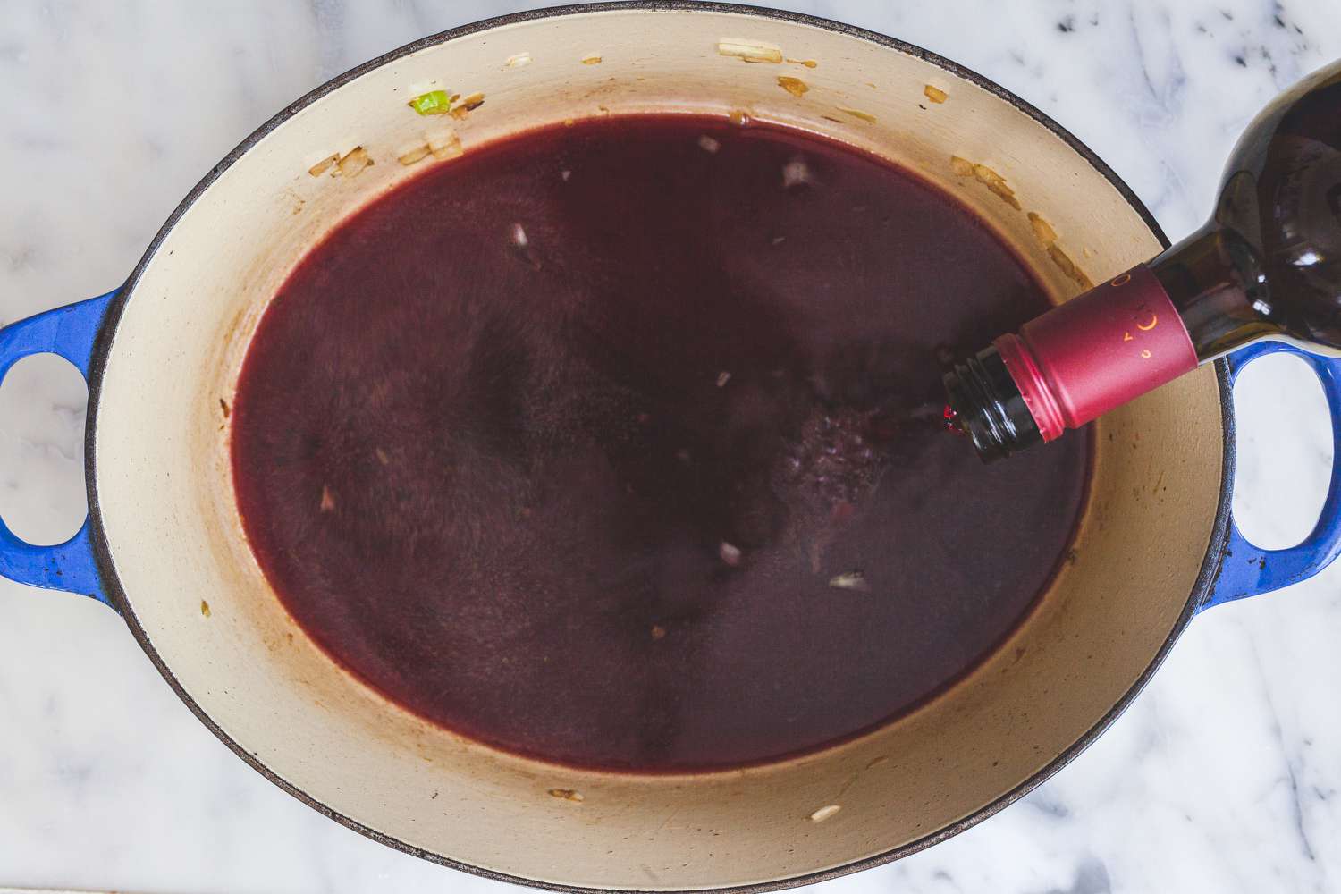 Adding wine to a dutch oven to make an oxtail recipe.