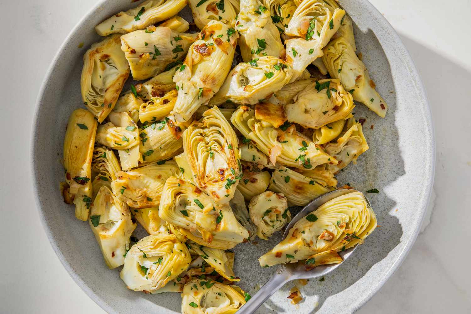 Closeup of a large serving plate with garlic & herb sautéed artichokes