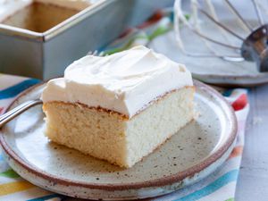 Easy white cake topped with frosting and on a plate.