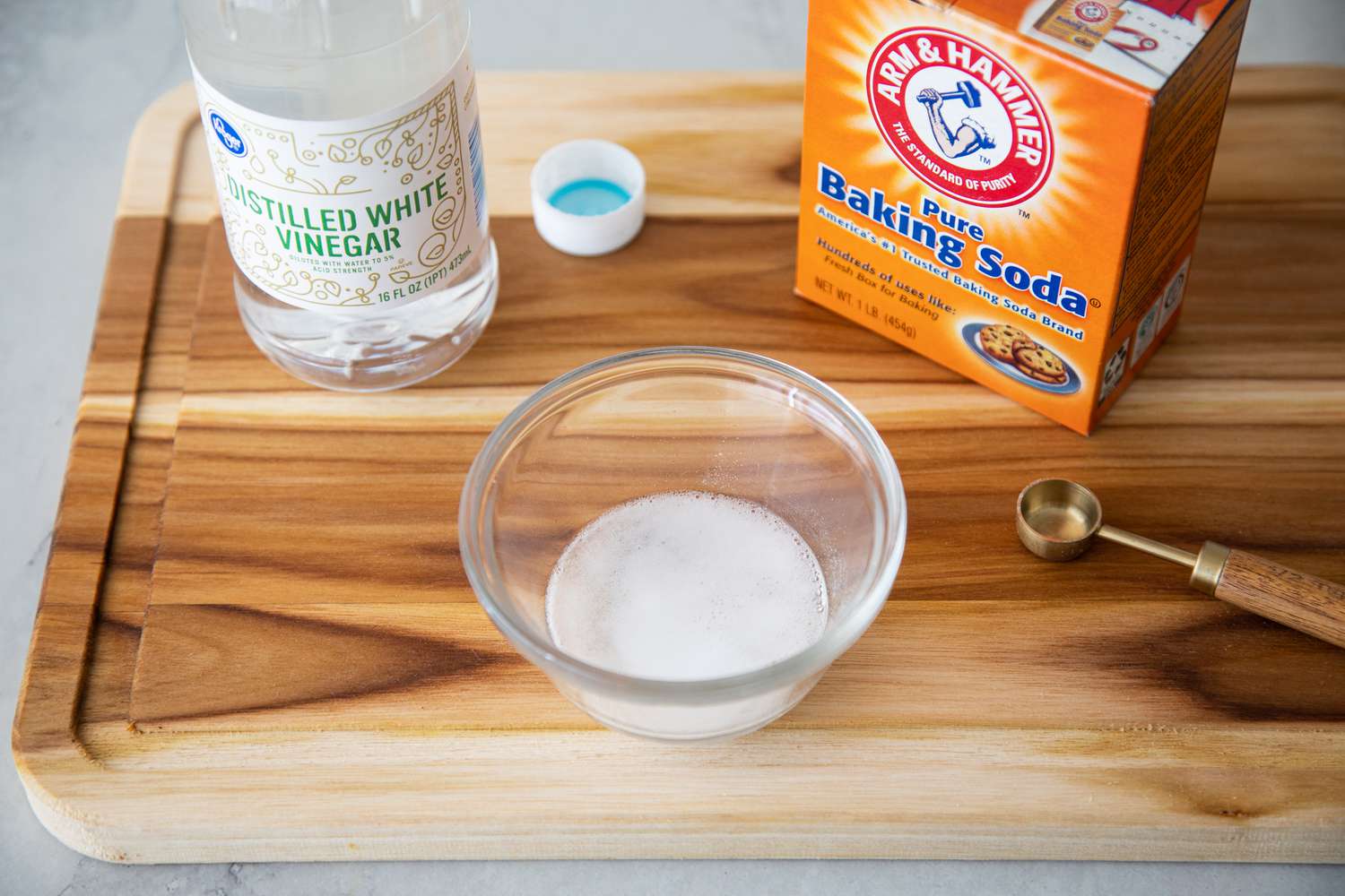 Box of Baking Soda and Bottle of White Vinegar Next to a Bowl with A Mixture of Baking Soda and Vinegar