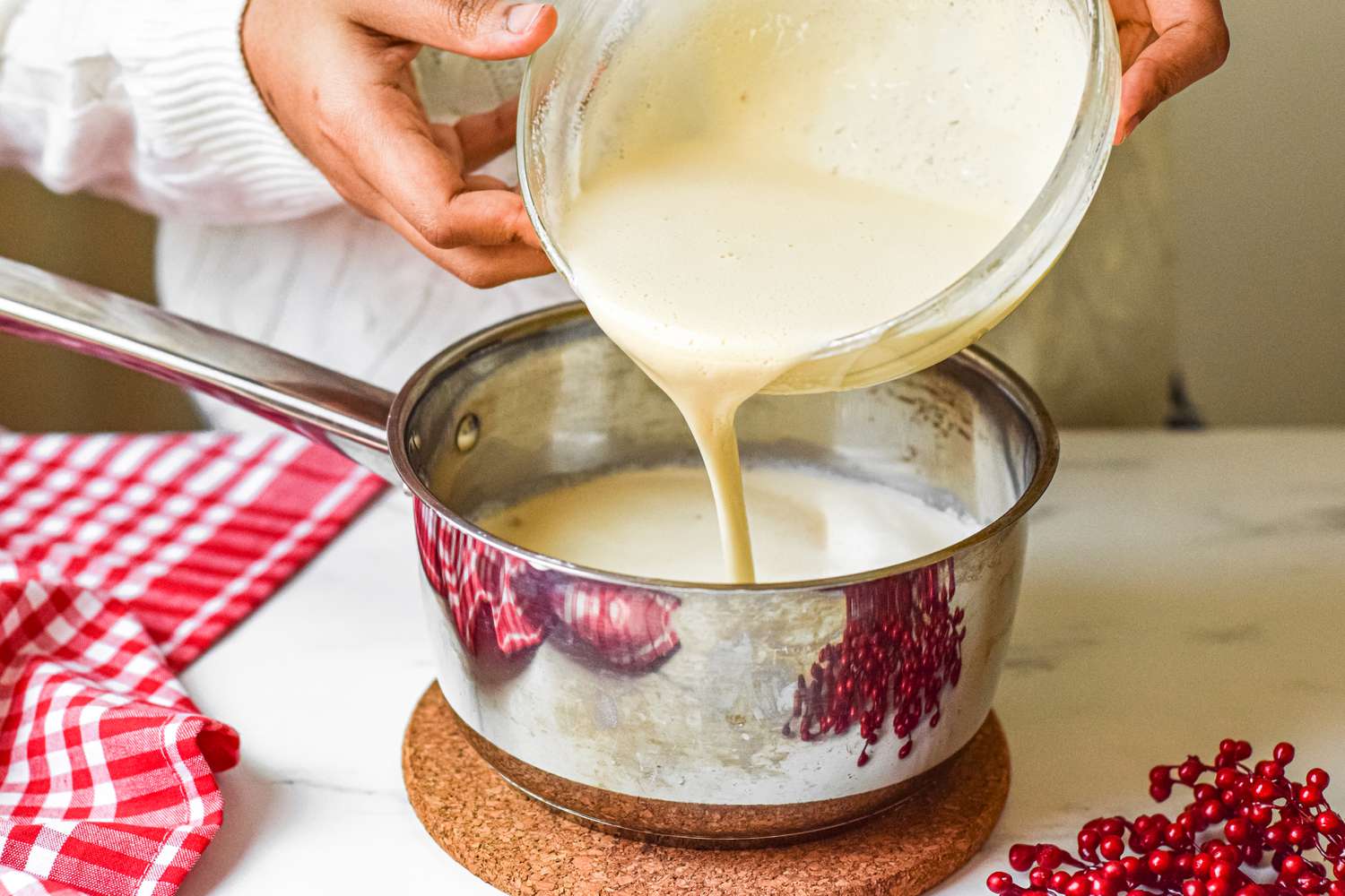Creamy eggnog being poured from a bowl into a cooking pot
