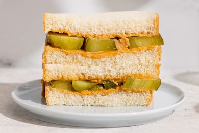 Peanut butter and pickle sandwich stacked on a white plate