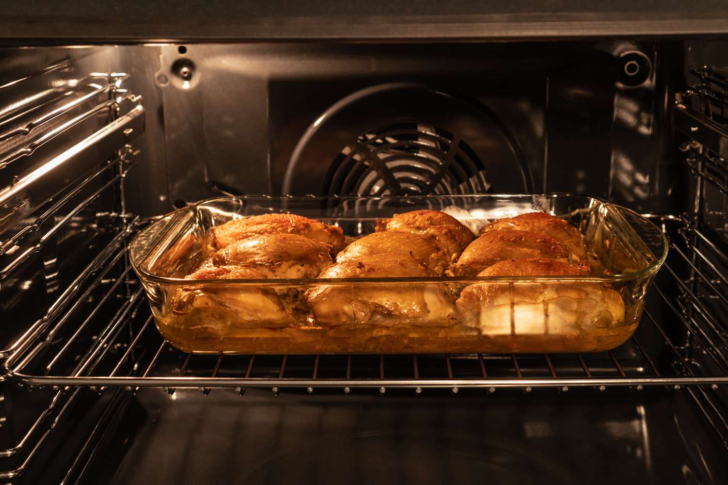 Roasting chicken thighs in a glass dish inside an oven heat and preparation visible