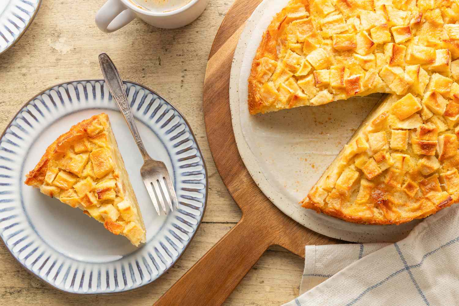 slice of Easy French Apple Cake on a dessert plate with a fork, cake on a serving board