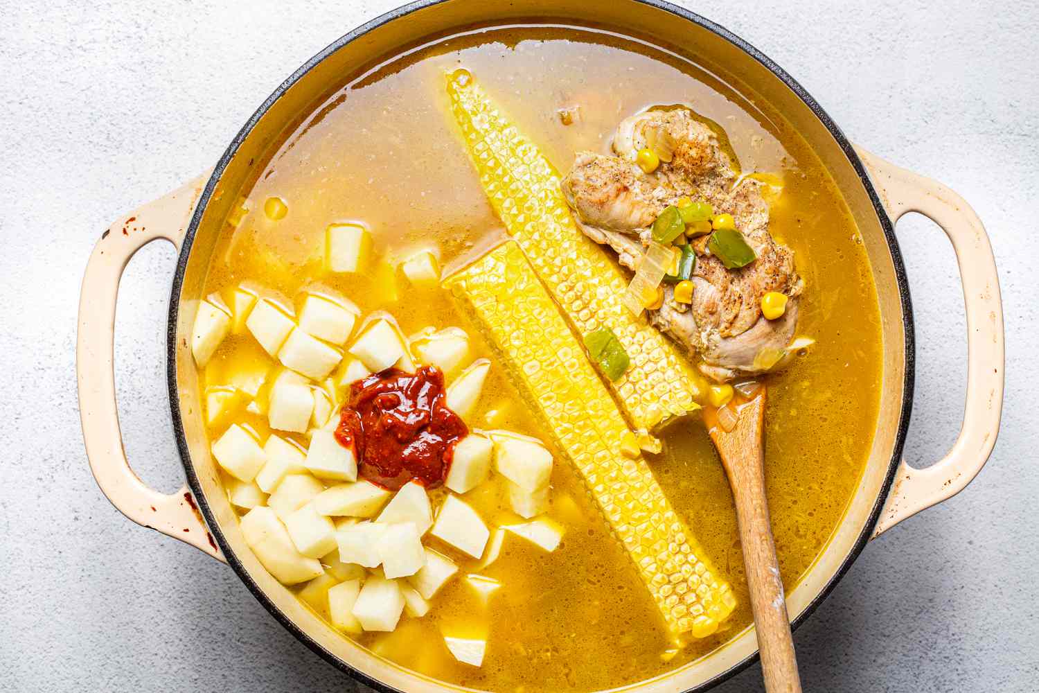 Corn Cobs, Potatoes, Chipotle Adobo Paste, and Chicken Stock Added to Dutch Oven for Chipotle Chicken Chowder Recipe