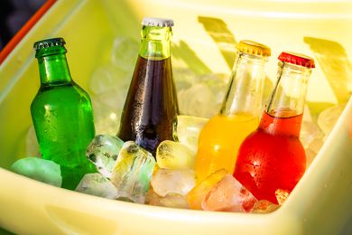 A cooler filled with ice and four beverage glass bottles