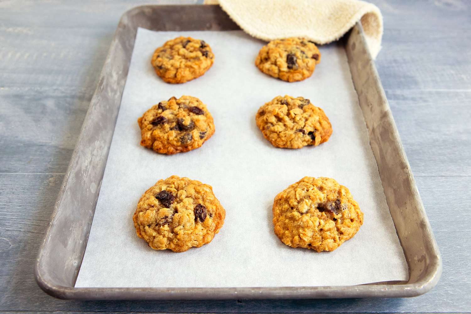 A tray with six oatmeal raisin cookies on parchment paper