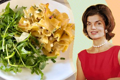 Jacqueline Kennedy next to a plate of pasta and arugula salad.