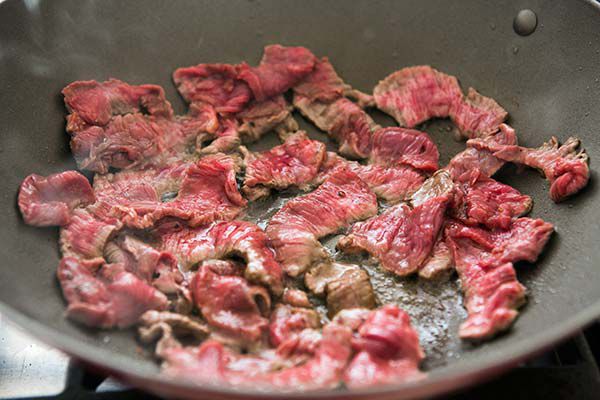 raw beef strips being cooked in wok
