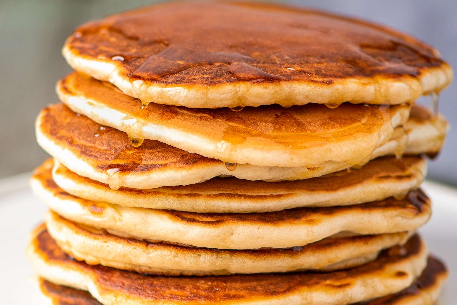 Stack of pancakes with syrup drizzled on top highlighting breakfast food presentation and texture focus