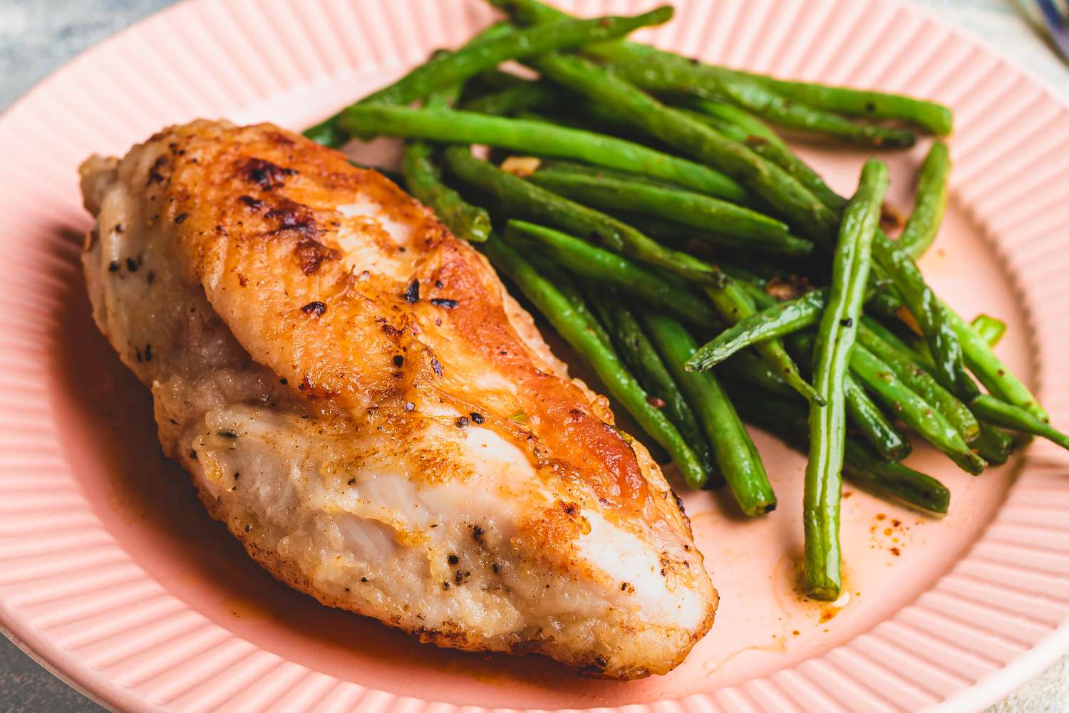 cooked chicken breast on a plate with green beans