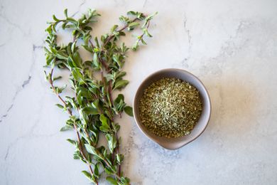 Bowl of Dry Marjoram Next to Sprigs of Fresh Marjoram