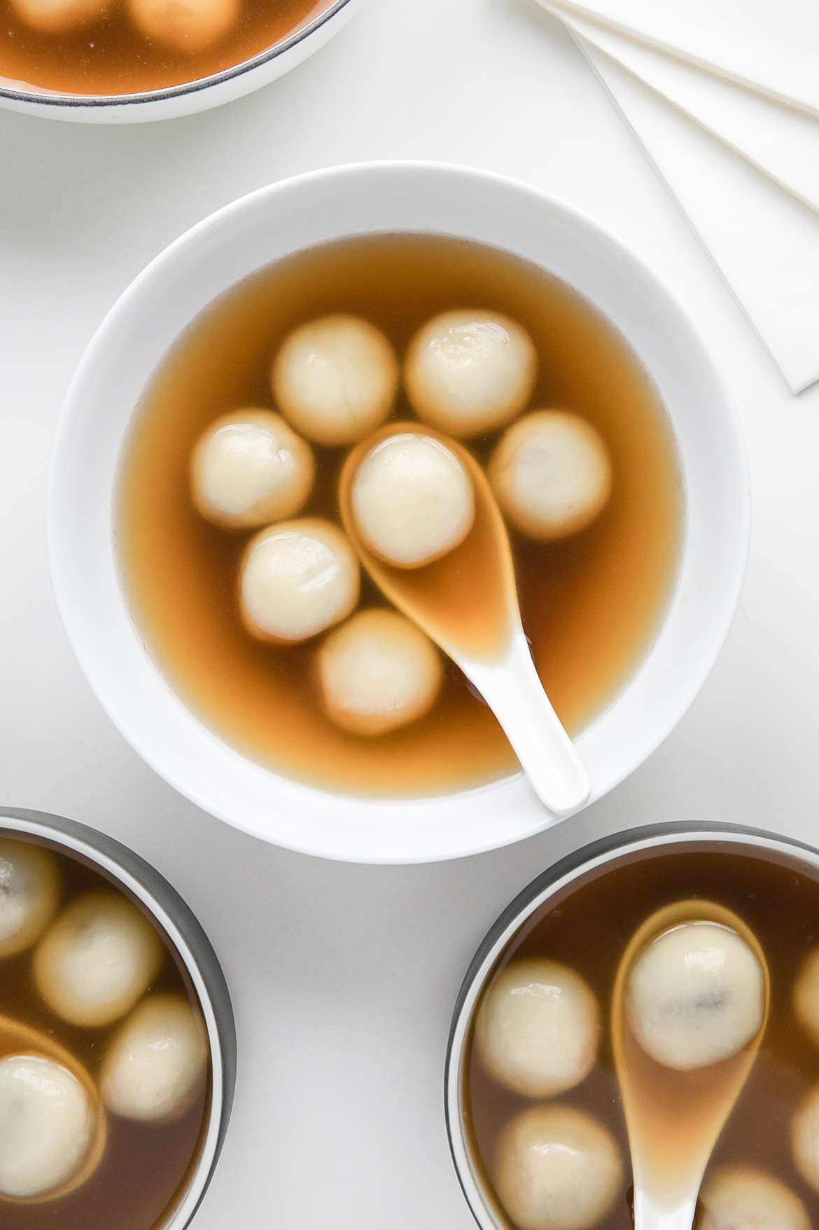 Three Bowls of Red Bean Tangyuan with Soup Spoons and a Pot with More 
