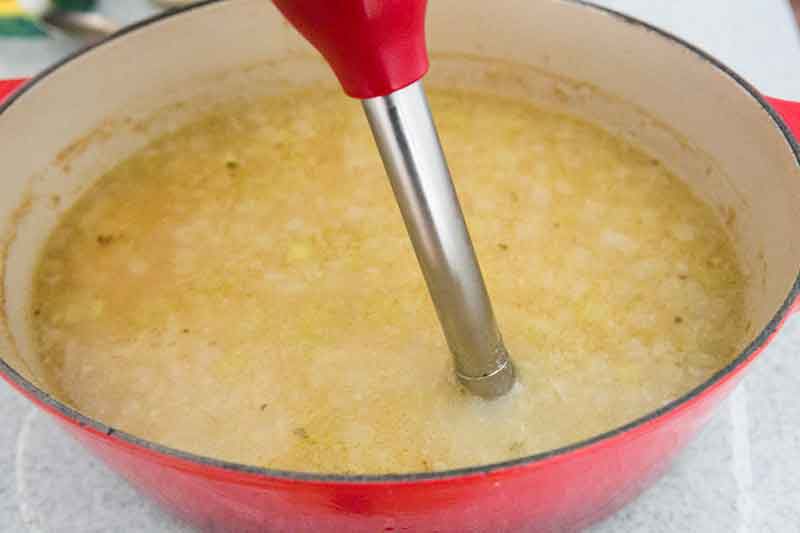 Ham and potato soup ingredients being blended together with an immersion blender