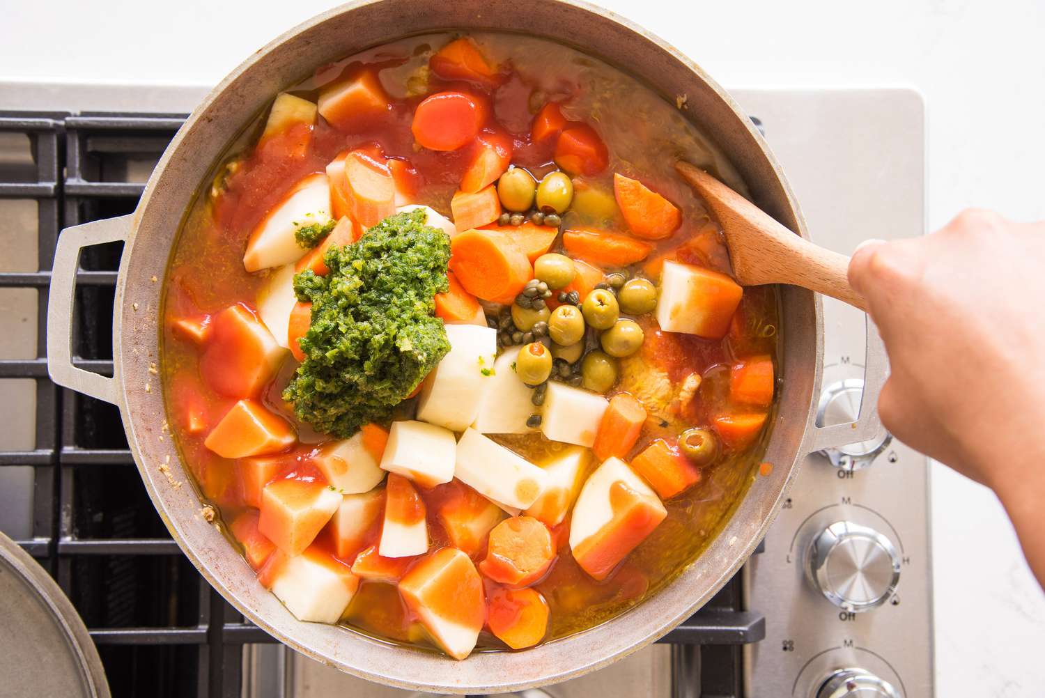 Vegetables, Recaito, Olives, Capers, and Can Tomato Sauce Stirred Into Caldero With Other Ingredients for Pollo Guisado Recipe